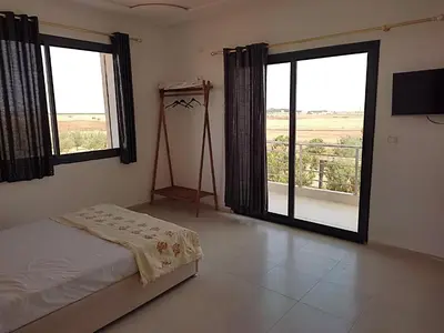 a bedroom with a bed and two large windows at Lina Village in Al Hachlaf