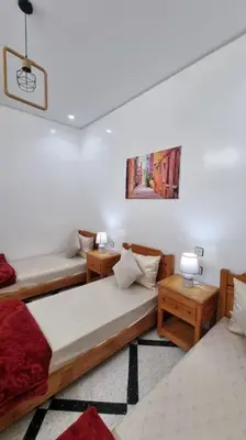 a room with two beds and two tables in it at Spacieux Appartement in Azrou