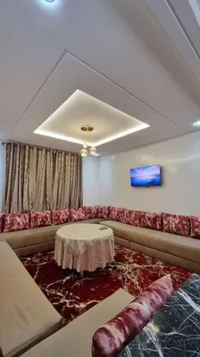 a living room with a red couch and a table at Spacieux Appartement in Azrou