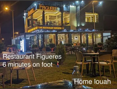 a restaurant with tables and chairs in front of a building at Home louah in Fès