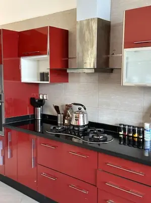 a kitchen with red cabinets and a black counter top at Super belle villa avec piscine in Fès