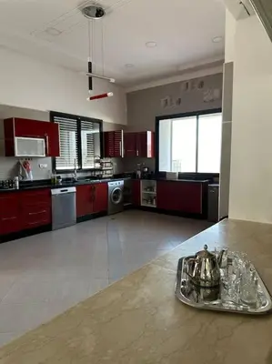 a large kitchen with red cabinets and a tray on a counter at Super belle villa avec piscine in Fès