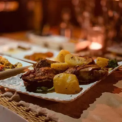 a plate of food with meat and potatoes on a table at Aurum Dunes Luxury Camp in Merzouga