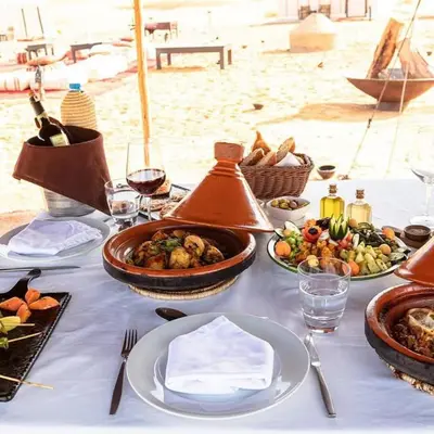 a table with plates of food on the beach at Aurum Dunes Luxury Camp in Merzouga