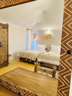a room with two beds and a mirror in it at Aurum Dunes Luxury Camp in Merzouga