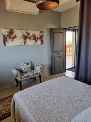 a bedroom with a bed and a chair and a window at Villa des Oliviers MEKNES in Meknès