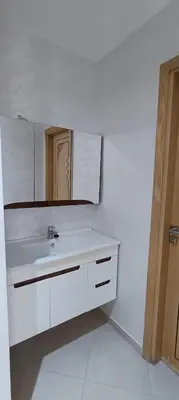 a white bathroom with a sink and a mirror at APPART-HOTEL La MAISON ATTAWBA 3 in Beni Mellal