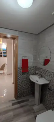a bathroom with a white sink and a red chair at APPART-HOTEL La MAISON ATTAWBA 3 in Beni Mellal