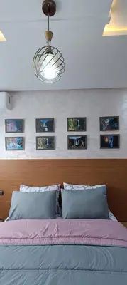 a bedroom with a bed with pictures on the wall at APPART-HOTEL La MAISON ATTAWBA 3 in Beni Mellal