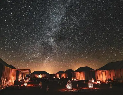 a starry night with a group of tents and the milky way at Luxurious Desert Camp in Merzouga