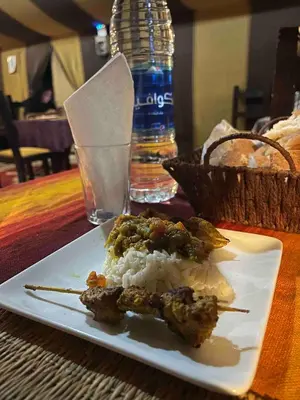 a plate of food with meat and rice on a table at Luxurious Desert Camp in Merzouga