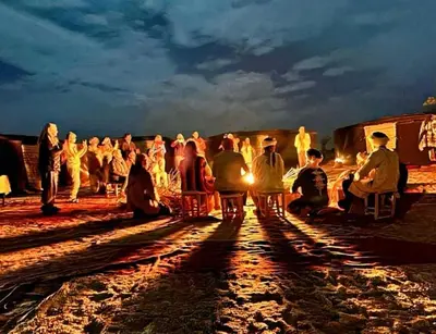 a group of people standing around in the desert at night at Luxurious Desert Camp in Merzouga