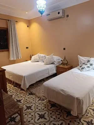 a bedroom with two beds and a chandelier at Gite Marbie maison rurale, une expérience naturelle unique, au coeur du moyen atlas, Maroc in Teklit