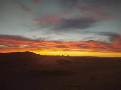 a sunset in the desert with the sky at Ecolodge Le désert in Kasr Bounou