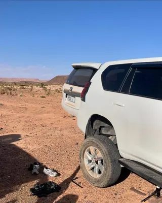 a white truck parked in the desert with a pair of shoes at Ecolodge Le désert in Kasr Bounou