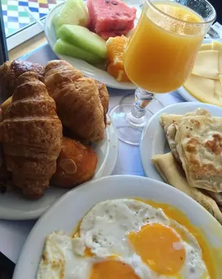 a table with plates of breakfast food and a glass of orange juice at Ecolodge Le désert in Kasr Bounou