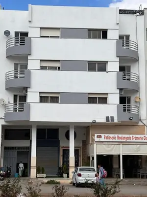 a white building with a car parked in front of it at Résidence el fassi in Fès