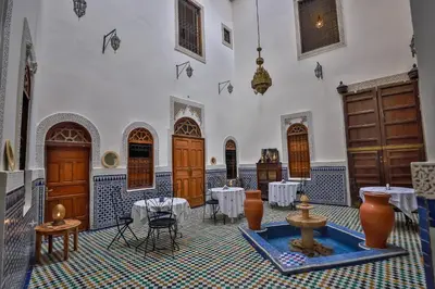 a room with tables and chairs in a building at Riad Nashira in Fès
