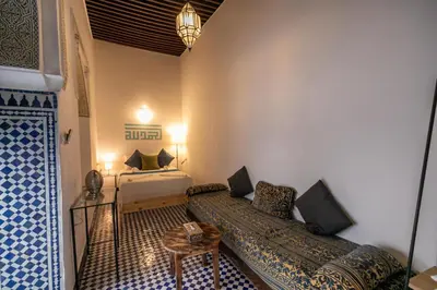 a room with two beds and a table in it at Riad Nashira in Fès