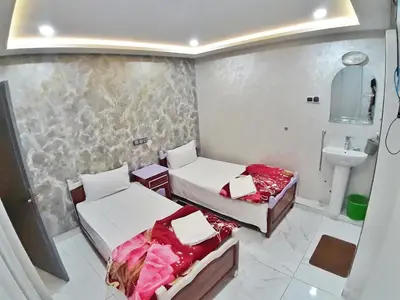 two beds in a small room with a sink at Hotel Restaurant Bougafer in Midelt