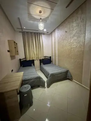 a bedroom with two beds and a table in it at Appartement fes magnifique in Fès