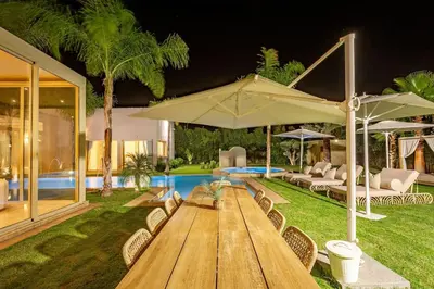 a wooden table with chairs and umbrellas next to a pool at Villa Bahamas , Luxe et élégance & piscine Chauffée, jacuzzi in Marrakech