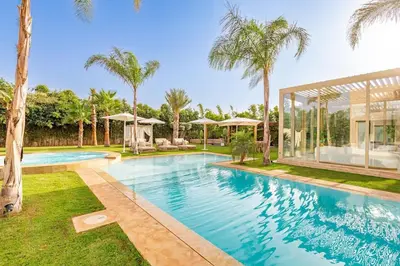a swimming pool with palm trees and a house at Villa Bahamas , Luxe et élégance & piscine Chauffée, jacuzzi in Marrakech