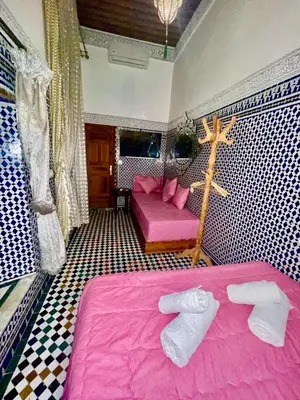 a room with a pink bed and a couch at RIAD LALJ Fes in Fès