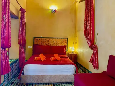 a bedroom with a red bed with red curtains at RIAD LALJ Fes in Fès