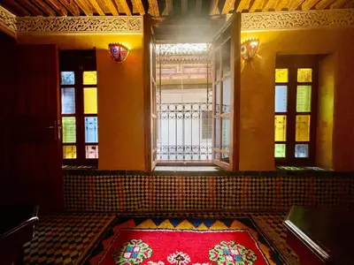 a room with a red rug in front of a window at RIAD LALJ Fes in Fès