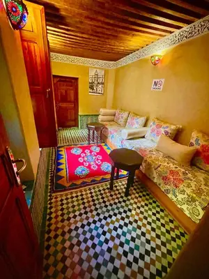 a living room with two beds and a table at RIAD LALJ Fes in Fès