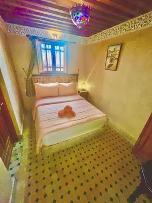 a bedroom with a bed with a pair of shoes on it at RIAD LALJ Fes in Fès
