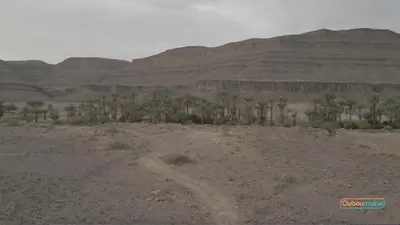 a dirt road in the desert with mountains in the background at Ouboumalne in Tamsahelt
