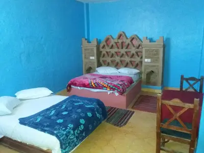 a bedroom with two beds in a blue room at Chez Belkacem in Merzouga