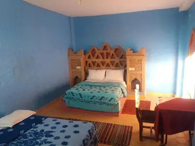 a bedroom with a bed and a table with a candle at Chez Belkacem in Merzouga