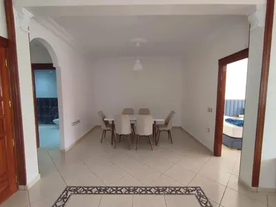 a white dining room with a table and chairs at Appartement Moderne 3 Chambres in Khemisset
