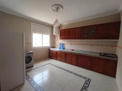 a kitchen with wooden cabinets and a microwave at Appartement Moderne 3 Chambres in Khemisset