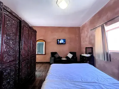 a bedroom with a bed and a chair and a window at Benyakoub in Mahirija