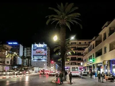 a city street at night with a palm tree and cars at Apartment Hamria Central in Meknès