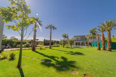 a park with palm trees and a house at Villa vue atlas marrakech in Marrakech