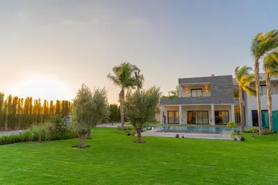 a house with a yard with palm trees at Villa vue atlas marrakech in Marrakech