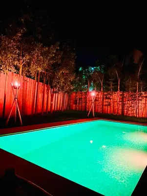 a swimming pool at night with lights on a fence at Villa Nadia Marrakech in Marrakech