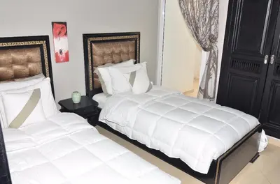 two beds in a bedroom with white sheets at Appartement au coeur de Fès in Fès