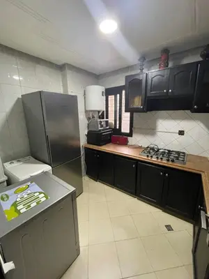 a kitchen with black cabinets and a stainless steel refrigerator at Appartement au coeur de Fès in Fès