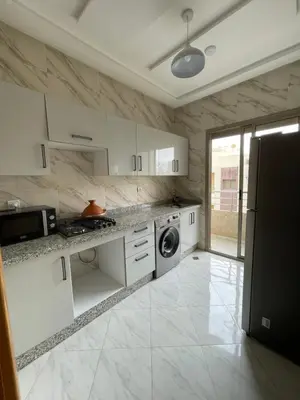 a kitchen with white cabinets and a washer and dryer at Housse Fez City in Fès
