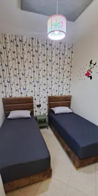 a bedroom with two beds and a chandelier at Appartement Calme et Jolie près de l'aéroport in Oulad Tayeb