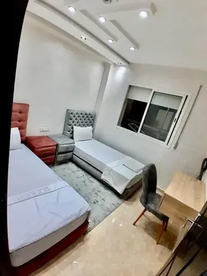 a room with two beds and a chair and a table at Meknes Luxe & Comfort in Meknès