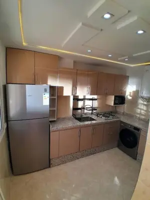 a kitchen with wooden cabinets and a stainless steel refrigerator at Meknes Luxe & Comfort in Meknès