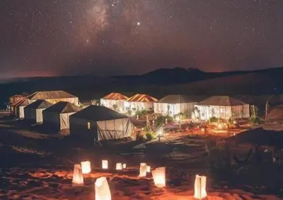 a group of tents in the desert at night at Luxury Camp in Merzouga