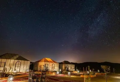a cluster of buildings under a starry sky at night at Luxury Camp in Merzouga